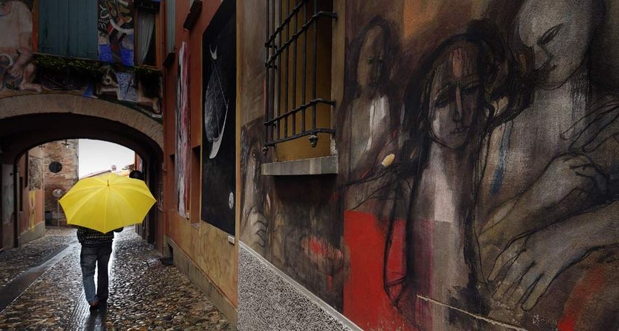Ein Spaziergänger passiert eine bemalte Hauswand in Dozza, Emilia Romagna, Italien