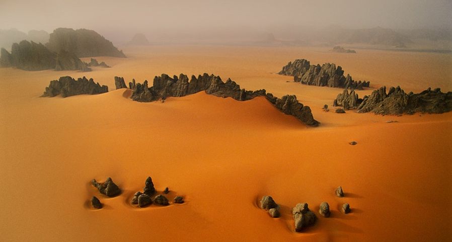 Spitze Sandsteine ragen aus orangenen Dünen im Karnasai-Tal, Republik Tschad –  George Steinmetz/Corbis ©