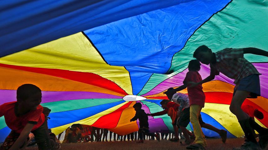 Unter einem Fallschirm spielende Kinder in Kalkutta, Indien, am Internationalen Tag der Freundschaft 