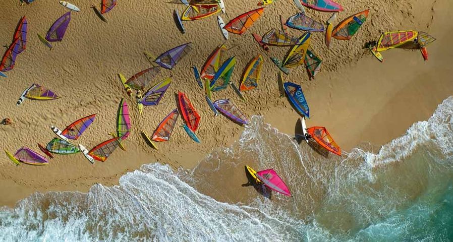 Surfbretter mit bunten Segeln liegen am Strand von Ho'okipa, Maui, Hawaii – Pacific Stock/Superstock ©