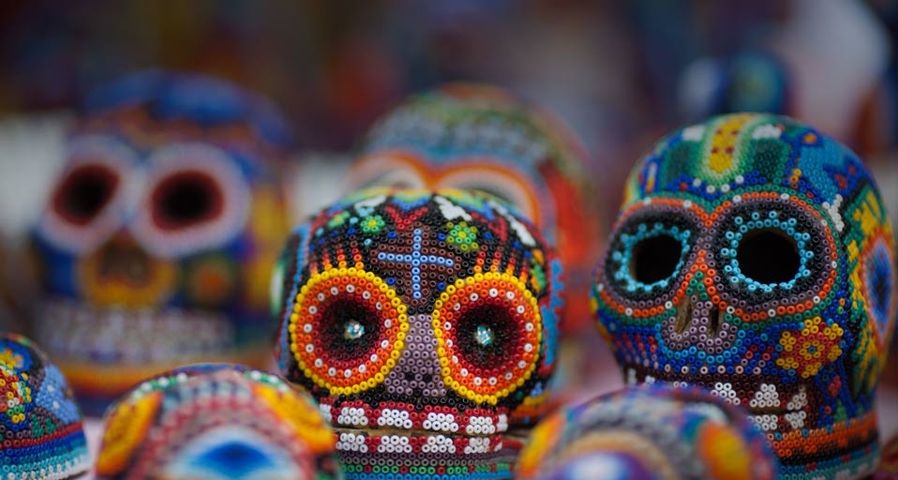 Bunte Totenköpfe – aus Perlen geformt – warten auf den Tag der Toten in Mexiko