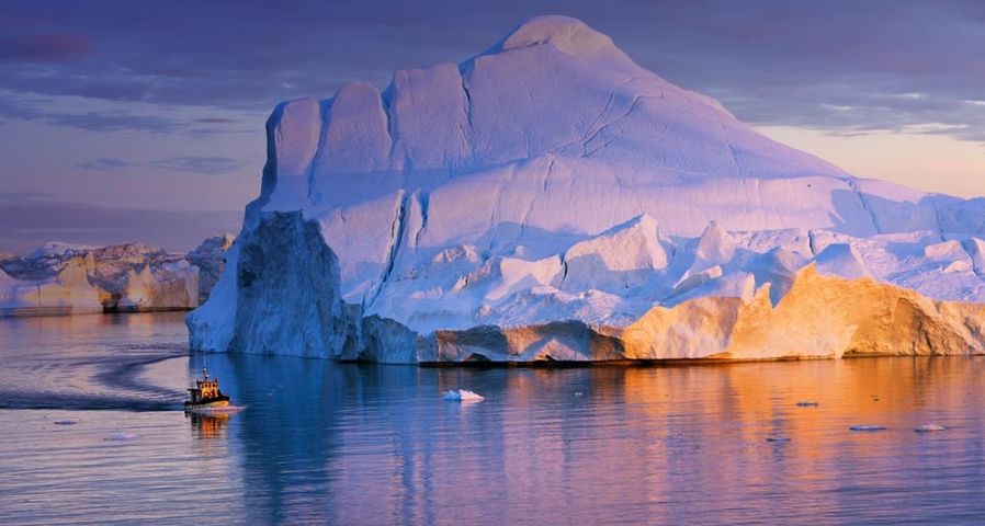 Ein Ausflugsschiff passiert einen riesigen Eisberg in der Diskobucht, Grönland – Frank Krahmer/Masterfile ©