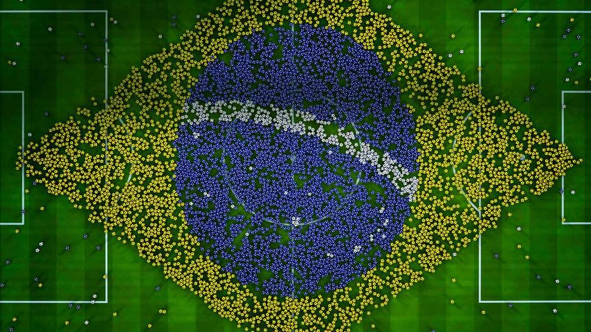 Eine gigantische Brasilien-Flagge geformt aus farbigen Bällen auf einem Fußballfeld