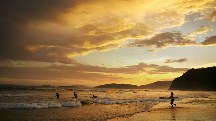 Surfer in der Abenddämmerung am Praia de Geriba, Buzios, Brasilien