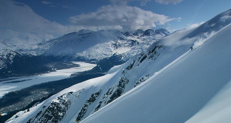 Ein Skifahrer bei der Abfahrt in einem unberührten Tiefschneehang bei Valdez, Alaska