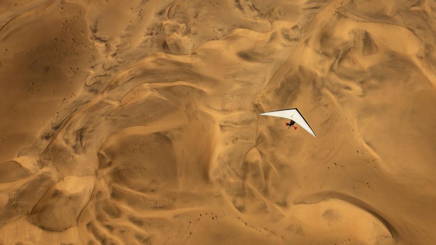 Ein Ultraleichtflugzeug fliegt über die Wüste Namibias